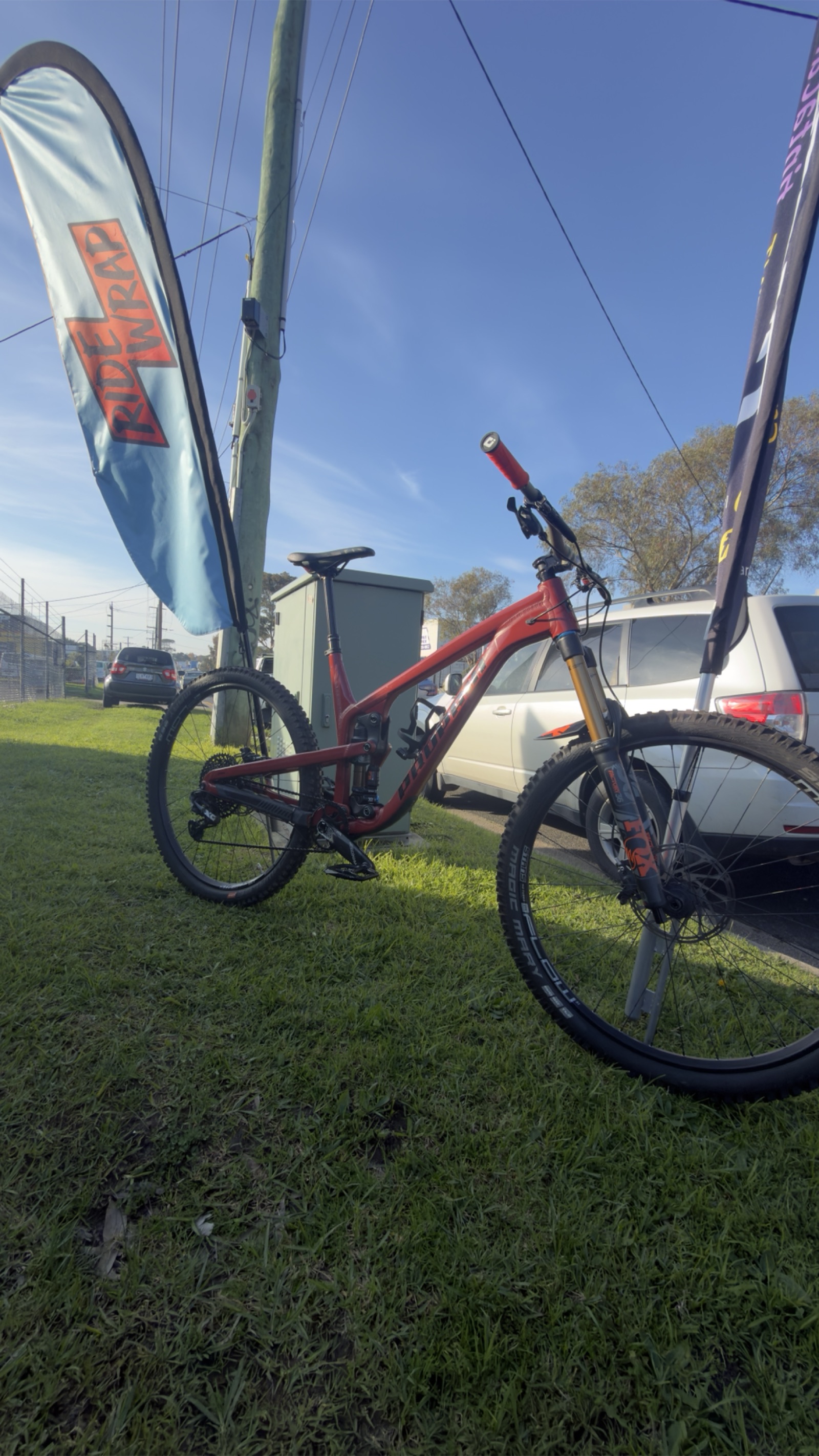 Red mountain bike displayed beside a RideWrap event flag